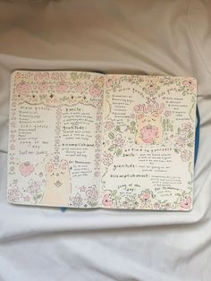 an open notebook with flowers and animals on it sitting on top of a white sheet