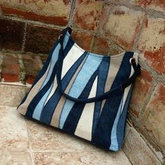 a blue and white striped purse sitting on the ground next to a brick wall,