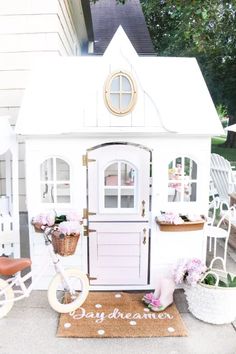 a white doll house with flowers and a bicycle