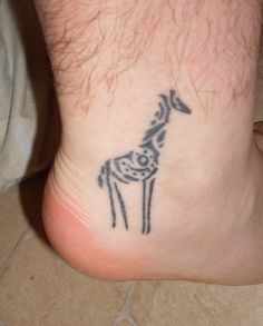 a small giraffe tattoo on the foot of a man