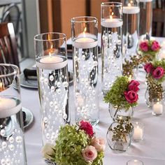 there are many vases with flowers and candles on the table