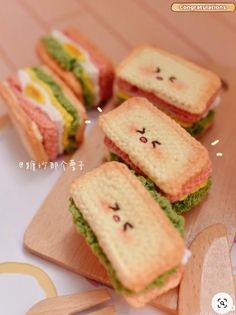 small sandwiches with faces drawn on them sitting on a cutting board