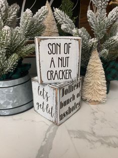 a sign that says son of a nut cracker sits on a table next to other christmas trees