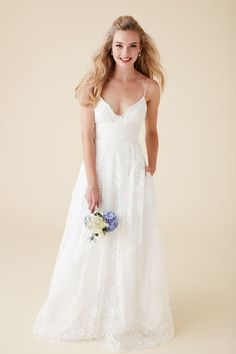 a woman in a white wedding dress holding a blue and white bouquet with her hand on her hip