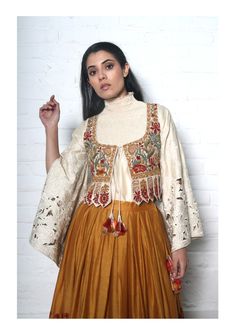 Editor's Note Featuring a mustard pleated lehenga with placement embroidery and ivory chanderi smocked top with cutwork on bell split sleeves with an embroidered waistcoat with tie-up detail. Color: Mustard Fabric: Chanderi Care: Dry Clean Only About the Designer Chandrima celebrates diversity in cultures and craft forms creating ready-to-wear women wear for the urban woman of today. The brand embodies the idea of Indian handloom and craft merged with an international style. Label Chandrima stan 2023 Embroidery, Combo Outfits, Navratri Outfits, Ivory Lehenga, Jacket Lehenga, Saree Drape, Fashion Garments, Pattern Outfits, Choli Designs