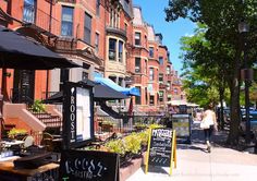 the sidewalk is lined with tables and umbrellas