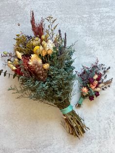 two bouquets of dried flowers sitting on the ground