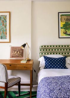 a bedroom with a bed, desk and chair in it next to a painting on the wall