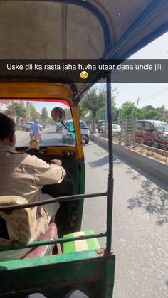 a man driving a green vehicle down a street next to a traffic filled with cars