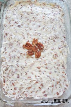 a casserole dish filled with cream cheese and pecans in the bottom layer