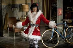 a woman in a red and white costume standing next to a bike