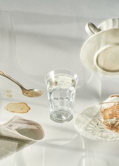 an assortment of dishes and utensils on a white tablecloth with water in the middle