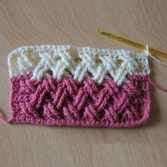 a pink and white crochet purse with a yellow knitting needle