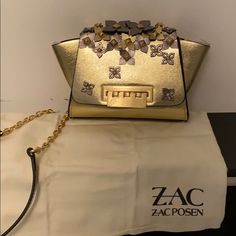 New With Tags Gold Leather Eartha Leather Mini Crossbody Bag From Zac Zac Posen Featuring A Detachable And Adjustable Shoulder Strap, A Top Flap Closure, An Internal Slip Pocket, An Embossed Internal Logo Stamp And Floral Appliqus. Condition New With Tag. Beautiful Neutral Colors But Quite A Statement Bag! Great For Any Outfit! Chic Gold Shoulder Bag With Silver-tone Hardware, Gold Party Bag With Branded Hardware, Chic Party Bags With Branded Hardware, Designer Tan Bags With Chain Strap, Chic Tan Shoulder Bag With Chain Strap, Chic Tan Bag With Chain Strap, Mini Chain Bag, Statement Bag, Zac Posen