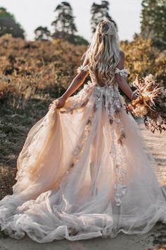 a woman in a wedding dress is walking through the woods with her back to the camera