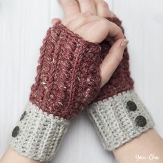 a woman's hand holding onto a pair of knitted wrist warmers with buttons