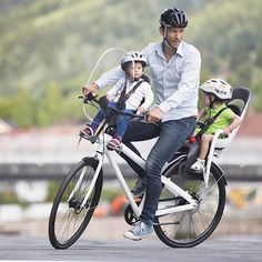 a man riding a bike with two children on the front and one is wearing a helmet