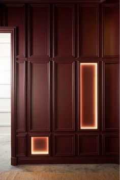 an empty room with dark wood paneling and neon lights on the wall, in front of a white door