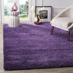 a purple rug in a living room next to a chair and vase with flowers on it