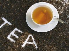 a cup of tea sitting on top of a white saucer next to the word tea