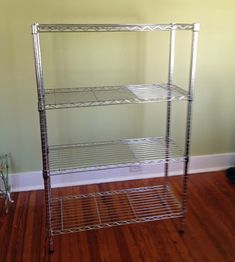 three tiered shelving unit in the corner of a room with hard wood flooring