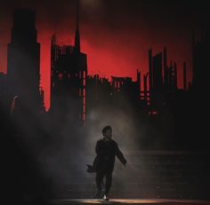 a man standing in front of a city skyline with red light coming from behind him