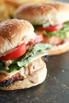 two chicken sandwiches with tomatoes, lettuce and cheese