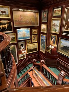 a staircase with paintings on the wall and wooden banisters in front of it