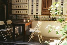 there is a small table and chairs on the porch with bottles in the back ground