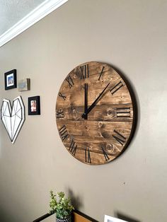 a large wooden clock mounted to the side of a wall next to pictures on the wall