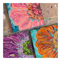 four colorful flower paintings on canvases sitting on top of each other in front of a wall