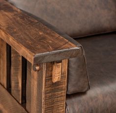 a brown leather couch with wooden arm rest