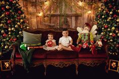 two children sitting on a couch in front of christmas decorations