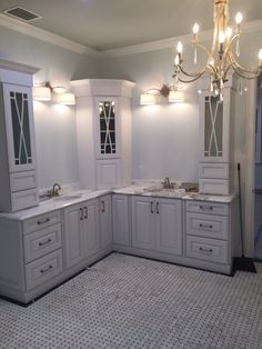 a bathroom with two sinks, cabinets and a chandelier