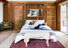 a person laying on top of a bed in a room with wood paneled walls