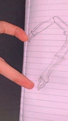 a person's hand is pointing at a piece of paper with a drawing on it