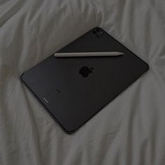 an apple laptop computer sitting on top of a white bed sheet with a pencil sticking out of it