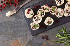 cranberry rolls with cream cheese and herbs on slate board next to utensils