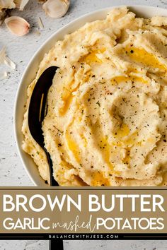 a bowl filled with mashed potatoes on top of a white table next to garlic