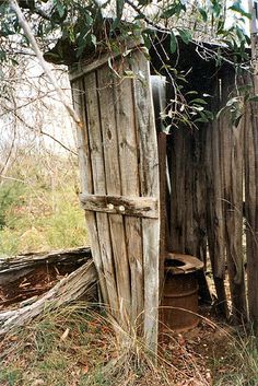 an old outhouse in the woods with its door open