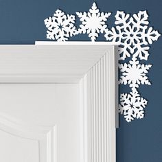 snowflakes are hanging on the wall next to a white door with blue walls