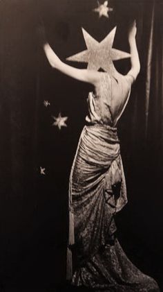 a black and white photo of a woman with stars on her head in the air