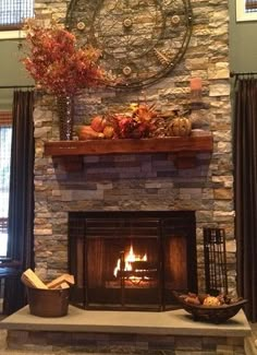 a stone fireplace in a living room with autumn decorations on the mantel above it