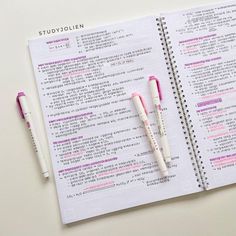 two pens sitting on top of an open notebook