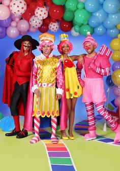 three people dressed up as clowns in front of balloons