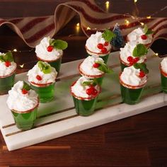 small cupcakes with whipped cream and cherries are arranged on a white tray