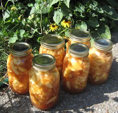 four jars filled with food sitting on the ground