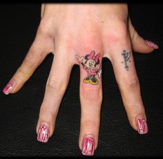 a person with minnie mouse tattoo on their hand and pink nail polishes around her fingers