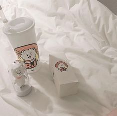 the baby bottle is next to the cup on the bed