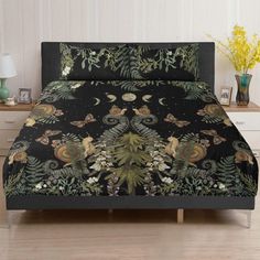 a bed with a black comforter covered in green leaves and animals on it's side